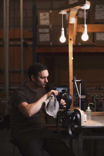 Man carefully wiping a component in a workshop with a light overhead